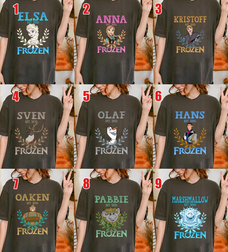 Puede incluir: Nueve camisetas de color gris oscuro con personajes de la pel&iacute;cula "Frozen". Cada camiseta tiene el nombre de un personaje, el texto "EST. 2013" y la palabra "FROZEN" en una fuente decorativa. Los personajes incluyen Elsa, Anna, Kristoff, Sven, Olaf, Hans, Oaken, Pabbie y Marshmallow.