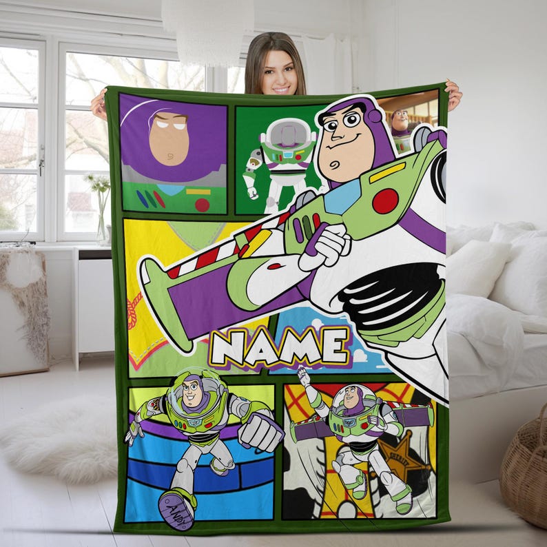 Puede incluir: Una manta rectangular de forro polar con un dise&ntilde;o de estilo c&oacute;mic que muestra varias ilustraciones del personaje Buzz Lightyear con su traje espacial blanco, verde y morado. La palabra NAME est&aacute; impresa en grandes letras blancas en el centro.