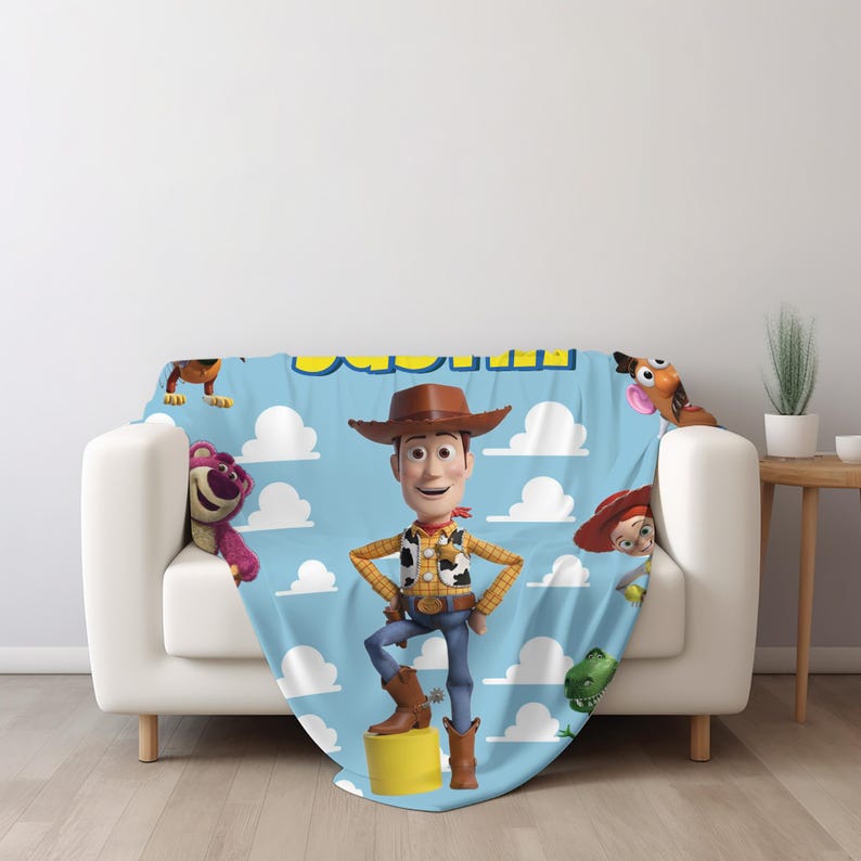 K&ouml;nnte beinhalten: Eine hellblaue Wohndecke mit einem sich wiederholenden wei&szlig;en Wolkenmuster und verschiedenen Toy Story-Figuren, darunter Woody in der Mitte, Lotso, Rex, Jessie und Mr. Potato Head. Die Decke zeigt den Schriftzug "Toy Story" in Gelb.