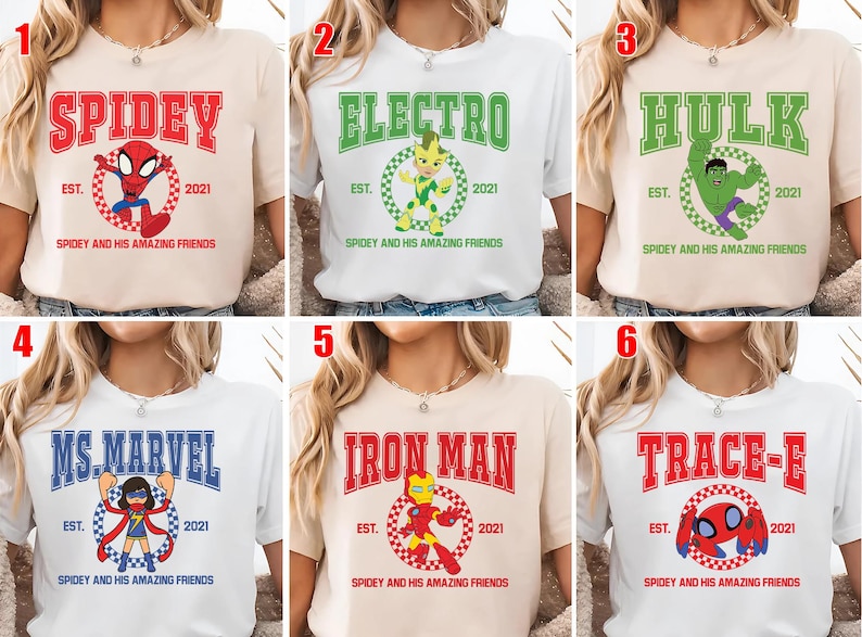 May include: A collection of six t-shirts featuring superhero-themed designs. Each shirt displays a different character's name in bold letters, along with a corresponding graphic and the text "Spidey and His Amazing Friends". The shirts are in various colors.