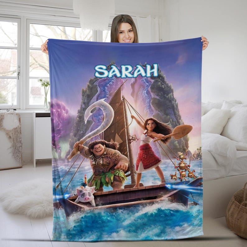 May include: A rectangular fleece blanket featuring a vibrant Moana-themed graphic with the name Sarah printed in blue at the top. The design depicts Moana and Maui on a wooden sailing boat on the ocean, accompanied by Pua and Heihei characters.