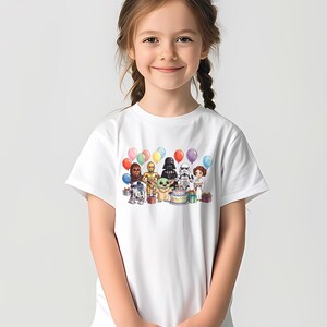 Puede incluir: Camiseta blanca con un dise&ntilde;o colorido de personajes de Star Wars, incluyendo a Chewbacca, C-3PO, Darth Vader y Baby Yoda, con globos y una tarta de cumplea&ntilde;os. El dise&ntilde;o est&aacute; centrado en la parte delantera.