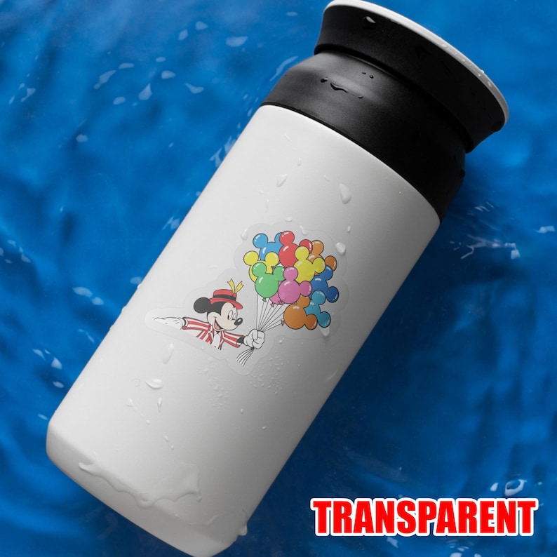 May include: White insulated tumbler with a black lid. A colorful sticker of Mickey Mouse holding balloons is on the side. The word "TRANSPARENT" is printed in red at the bottom. The tumbler is on a blue surface.