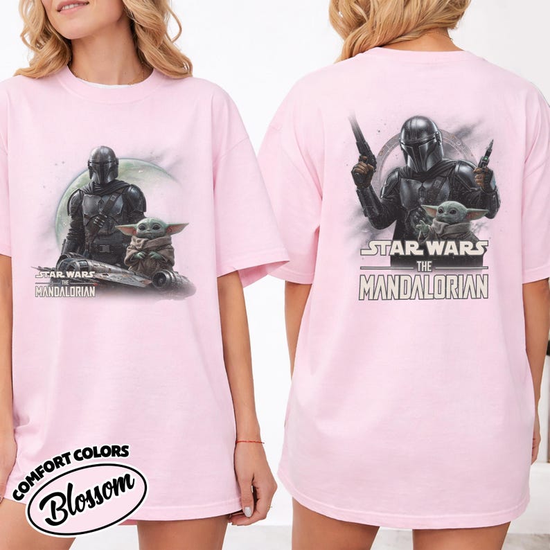 Puede incluir: Camiseta rosa claro con un dise&ntilde;o de Star Wars. La parte delantera muestra a The Mandalorian y Grogu con el texto "STAR WARS THE MANDALORIAN". La parte trasera muestra a The Mandalorian con armas, Grogu y el mismo texto.