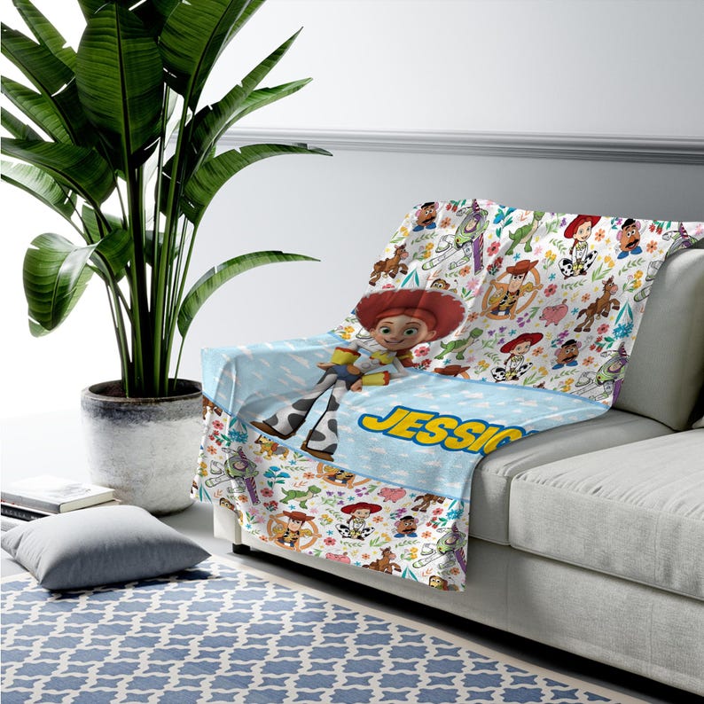 May include: A soft throw blanket featuring a repeating pattern of Toy Story characters including Woody, Buzz Lightyear, Jessie, and Mr. Potato Head. The blanket has a light blue section with the name JESSICA printed in bold yellow letters.