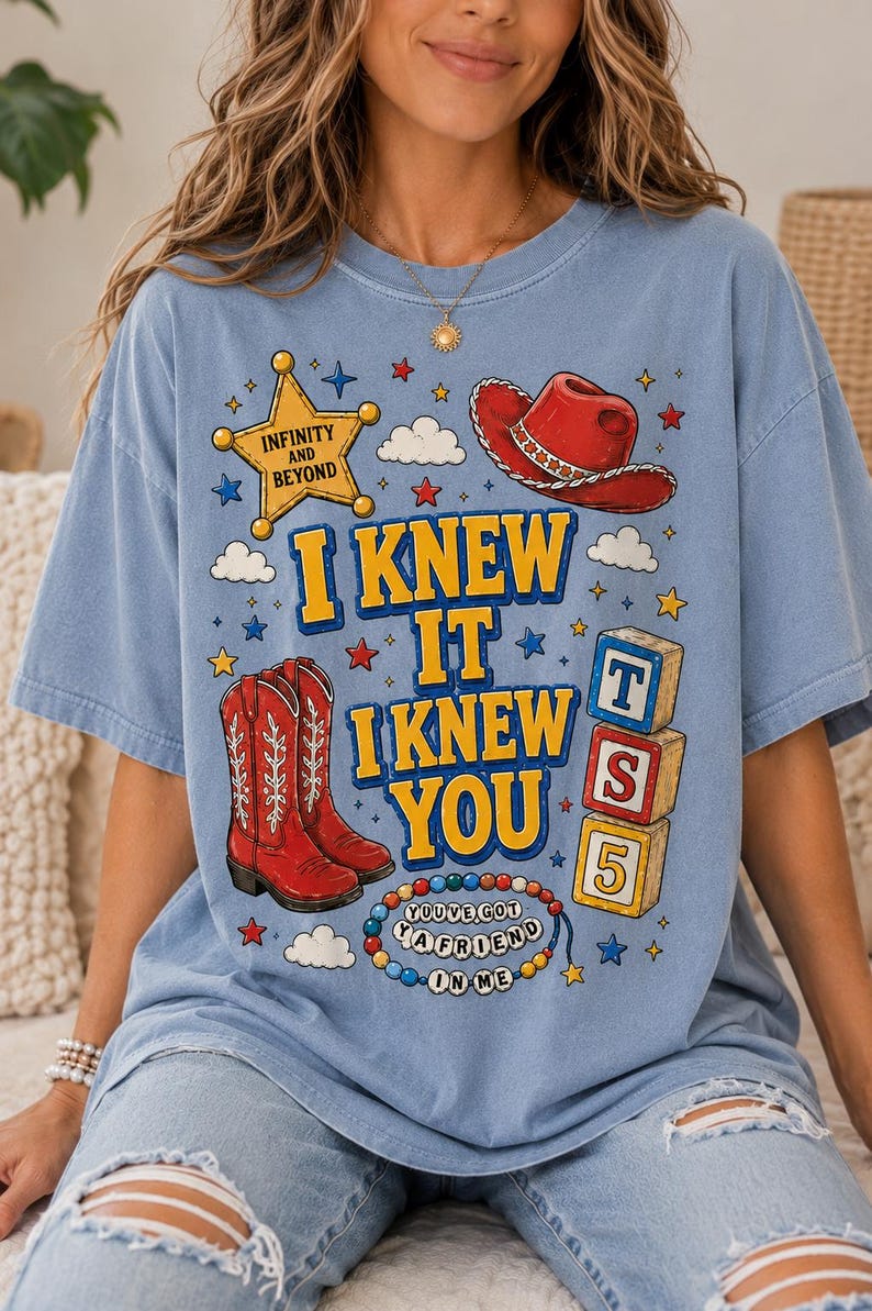 May include: A light blue t-shirt featuring a graphic print with a yellow sheriff star labeled INFINITY AND BEYOND, a red cowboy hat, red cowboy boots, three stacked alphabet blocks with T, S, 5, and a beaded necklace with YOU'VE GOT A FRIEND IN ME.