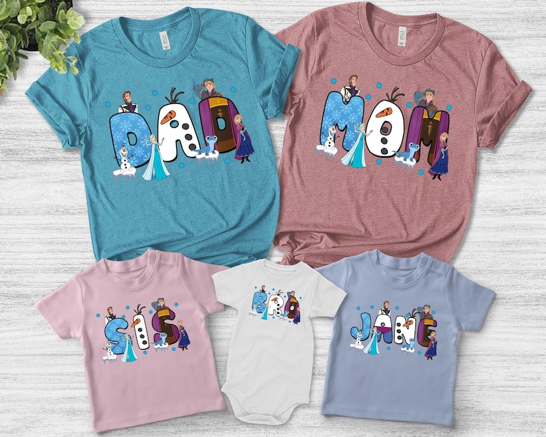 May include: A collection of family-themed t-shirts and a baby onesie. The shirts are in various colors, including blue, pink, and white, each displaying a different name: "Dad," "Mom," "Sis," "Jane," and "Baby." The designs feature characters from a popular animated movie.