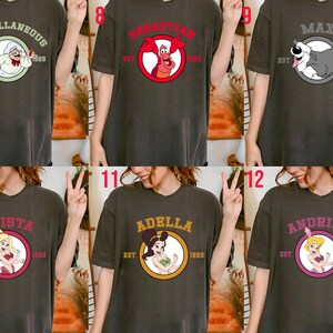 Puede incluir: Camisetas de color gris oscuro con varios dise&ntilde;os de personajes de dibujos animados. Los dise&ntilde;os incluyen personajes como la Sra. Potts, Sebasti&aacute;n el cangrejo, Max el perro, Arista, Adella y Andrina. Cada dise&ntilde;o est&aacute; en un marco circular con el texto "EST 1989".