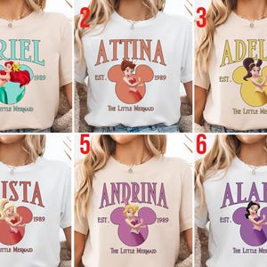 Puede incluir: Seis camisetas con diferentes nombres de la pel&iacute;cula "La Sirenita". Cada camiseta tiene un nombre en una fuente estilizada sobre una cabeza de Mickey Mouse con una princesa dentro. Tambi&eacute;n se incluye el texto "EST. 1989" y "The Little Mermaid".