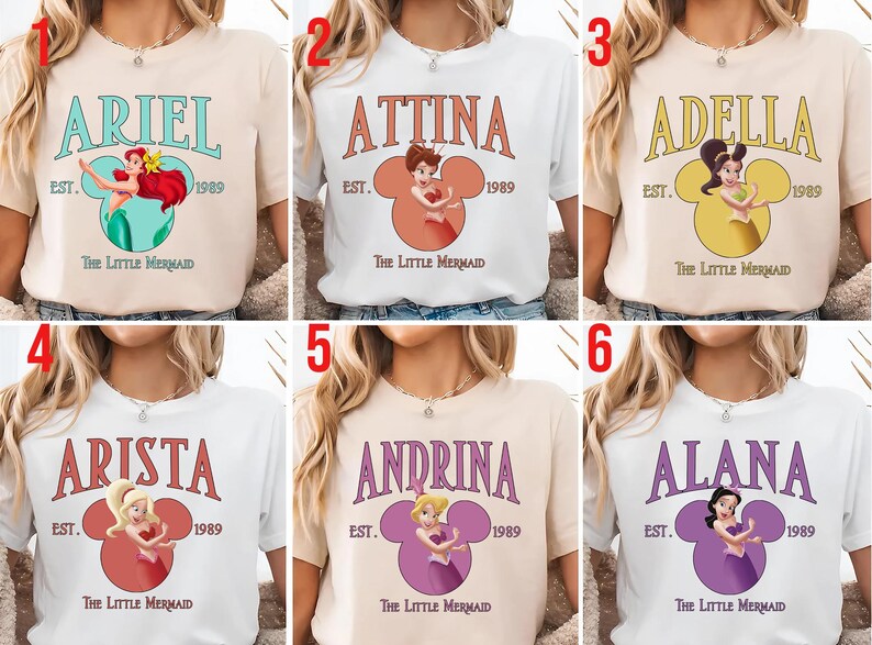 Puede incluir: Seis camisetas con diferentes nombres de la pel&iacute;cula "La Sirenita". Cada camiseta tiene un nombre en una fuente estilizada sobre una cabeza de Mickey Mouse con una princesa dentro. Tambi&eacute;n se incluye el texto "EST. 1989" y "The Little Mermaid".