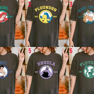 Puede incluir: Seis camisetas de color gris oscuro con dise&ntilde;os de personajes de dibujos animados. Cada camiseta tiene un nombre de personaje diferente en un c&iacute;rculo, como "Ariel" y "Flounder", con "EST. 1989" debajo. Las camisetas son usadas por una persona.
