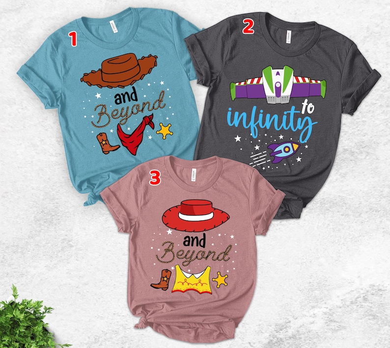 May include: Three graphic t-shirts. One is light blue with a cowboy hat, boots, and the words "and Beyond". Another is dark gray with a Buzz Lightyear design and the words "to infinity". The third is pink with a cowboy hat and the words "and Beyond".