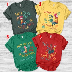 Op de afbeelding: Vier T-shirts met korte mouwen met cartoonhaan-afbeeldingen en tekst. De shirts zijn in donkergroen, geel, groen en rood. De tekst bevat "HEI GIRL", "DON'T BE A PEEKER", "HEI HEI IS MY SPIRIT ANIMAL" en "It's a hei hei Kind Of day".