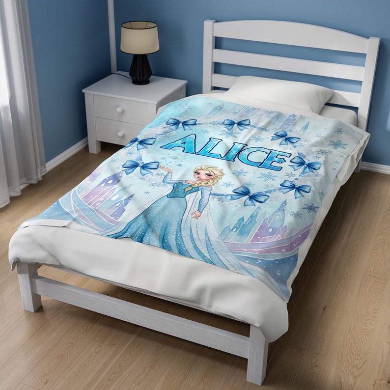 May include: A light blue fleece blanket featuring a cartoon character with blonde hair in a blue gown, surrounded by blue bows, snowflakes, and castle silhouettes. The name ALICE is printed in large blue letters across the center of the blanket.