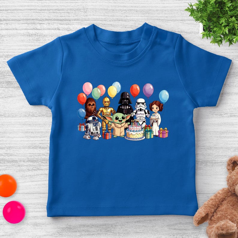 Puede incluir: Una camiseta azul con un gr&aacute;fico colorido de personajes de Star Wars, globos, regalos y una tarta de cumplea&ntilde;os. El dise&ntilde;o incluye personajes como Darth Vader, Yoda y R2-D2, ideal para una celebraci&oacute;n de cumplea&ntilde;os.