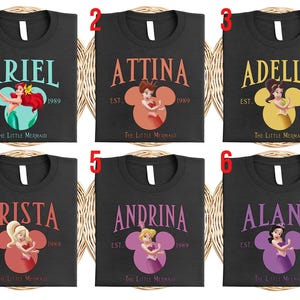 Puede incluir: Camisetas negras con nombres de "La Sirenita". Cada camiseta muestra un nombre, una ilustraci&oacute;n de personaje dentro de una cabeza de Mickey Mouse y el texto "EST. 1989". Los nombres incluyen Ariel, Attina, Adella, Arista, Andrina y Alana.