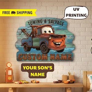 Puede incluir: Un letrero de madera con un cami&oacute;n de remolque de dibujos animados con el texto "TOWING & SALVAGE" y "CUSTOM NAME". El letrero est&aacute; pintado con un fondo azul y verde desgastado. Tambi&eacute;n se muestra el texto "YOUR SON'S NAME".
