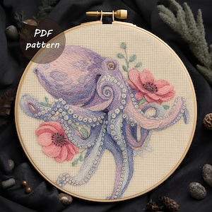 May include: An embroidered octopus design in a wooden hoop. The octopus is depicted in shades of purple and pink, with blue detailing, and is surrounded by pink flowers and green foliage. The text "PDF pattern" is visible.