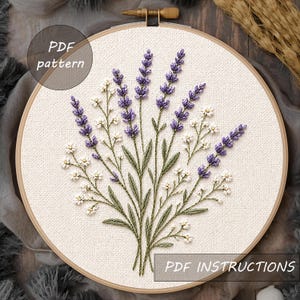 May include: A circular wooden embroidery hoop containing a fabric panel with a hand-stitched floral design of purple lavender sprigs and small white flowers with green stems. The text PDF pattern and PDF INSTRUCTIONS are visible on the image.