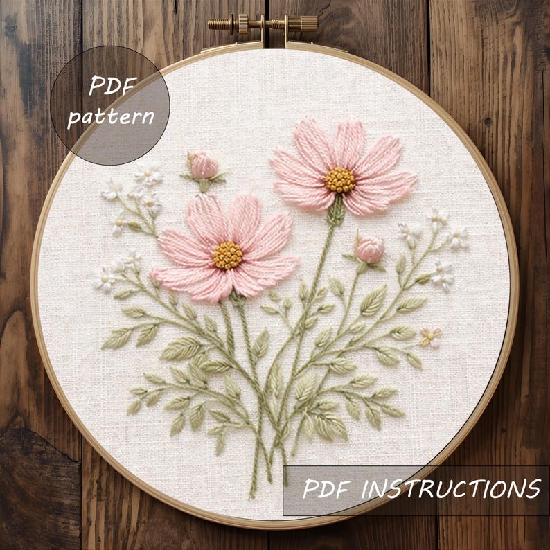 Puede incluir: Un bastidor de bordado con flores de cosmos rosas con centros amarillos y hojas verdes. El texto "PDF pattern" y "PDF instructions" es visible. El bordado est&aacute; en un bastidor de madera.