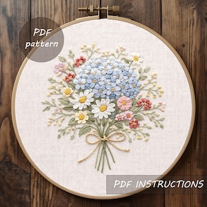 May include: Embroidered floral design featuring a bouquet of blue hydrangeas, daisies, and other colorful flowers. The embroidery is set in a wooden hoop, with the text "PDF pattern" and "PDF instructions".