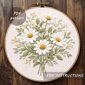 May include: Embroidered daisy floral design on a white fabric, set in a wooden embroidery hoop. The daisies have white petals and yellow centers, with green leaves and stems. Text on the image reads "PDF pattern" and "PDF instructions".