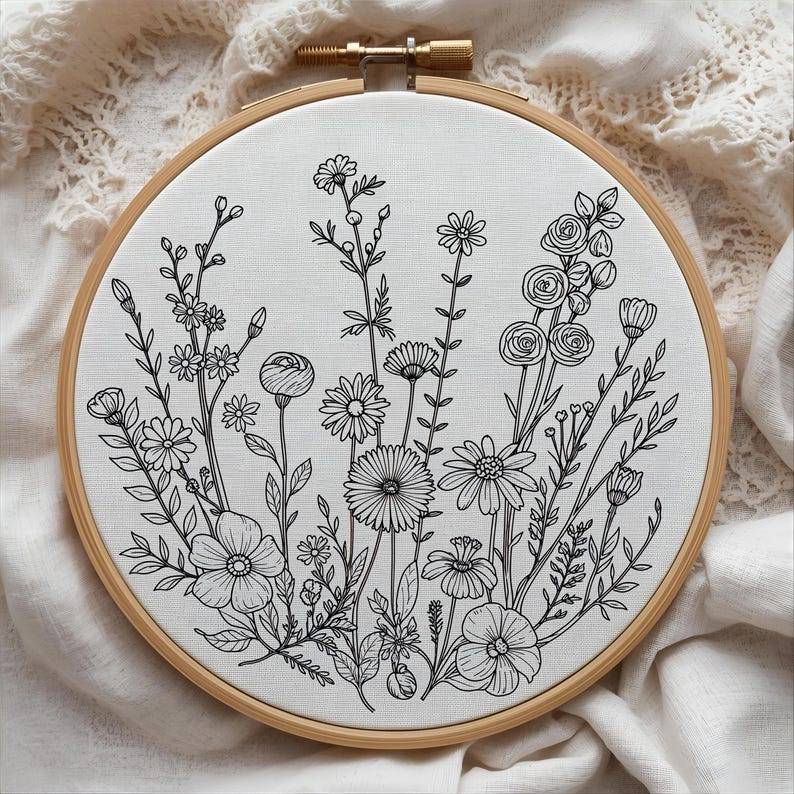 K&ouml;nnte beinhalten: Ein Stickrahmen mit einem schwarz-wei&szlig;en Blumendesign. Das Kunstwerk zeigt eine Vielzahl von Wildblumen, darunter G&auml;nsebl&uuml;mchen und Rosen, auf einem wei&szlig;en Stoff. Das Design wird von einem Holzrahmen umschlossen.