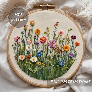 Può includere: Un colorato telaio da ricamo floreale con una varietà di fiori cuciti in tonalità di rosso, arancione, giallo, rosa, viola e blu. Il testo "PDF pattern" e "PDF instructions" è visibile. Il ricamo è in un telaio di legno.