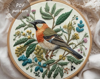 May include: Embroidered bird and floral design in a wooden hoop. The bird features orange, green, and brown feathers, surrounded by green leaves, blue and pink flowers. The text "PDF pattern" is in a circle at the top left.