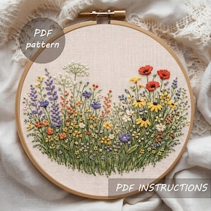 Könnte beinhalten: Gesticktes Blumendesign in einem Holzreifen. Das Kunstwerk zeigt eine lebendige Wiese mit bunten Blumen, darunter rote Mohnblumen, gelbe Sonnenhüte und lila Lavendel. Der Text "PDF pattern" und "PDF instructions" sind sichtbar.