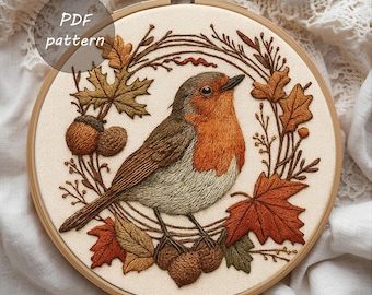 May include: Embroidered artwork of a robin bird surrounded by autumn leaves and acorns, set within a wooden embroidery hoop. The bird has a red breast, brown wings, and a gray belly. The text "PDF pattern" is visible.