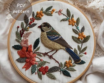 May include: Embroidered bird and floral design in a wooden hoop. The bird features tan, blue, and green details, perched on a branch surrounded by colorful flowers and leaves. The text "PDF pattern" is in the upper left corner.