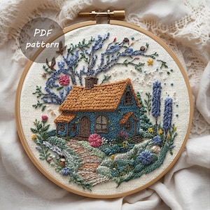 Puede incluir: Arte de aro bordado que presenta una casa azul con tejado marrón, rodeada de un jardín y un camino. La obra de arte incluye un árbol con flores azules y rosas. El texto "PDF pattern" es visible.