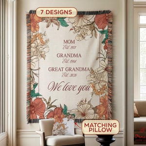 May include: A beige tapestry with floral designs in orange, peach, and green, framed by a dark border and fringe. Text includes "MOM," "GRANDMA," and "GREAT GRANDMA," with established dates and "We love you." A matching pillow is also shown.