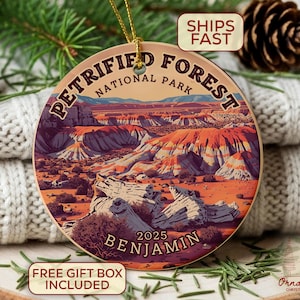 May include: A round ceramic ornament featuring a landscape illustration of Petrified Forest National Park. The ornament has a gold string for hanging and includes the text "Petrified Forest National Park" and "2025 Benjamin".