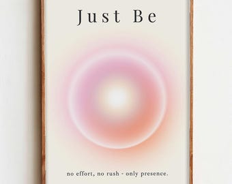May include: A framed art print with the words "Just Be" at the top. The artwork features a soft, circular gradient in shades of pink, orange, and white. The bottom of the print reads "no effort, no rush - only presence."