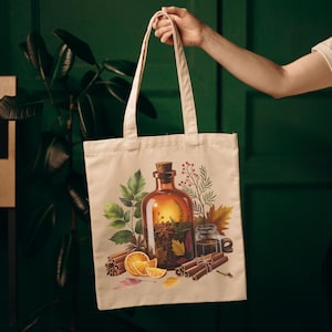 Puede incluir: Un bolso tote beige con una ilustración de acuarela de una botella de boticario marrón con un corcho, rodeada de palitos de canela, rodajas de naranja y hojas de otoño. El bolso tiene asas largas.