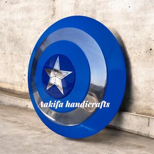 May include: A blue and silver shield with a central star design. The shield has concentric circles in blue and silver. The text "Aakifa handicrafts" is visible on the shield.