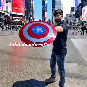 May include: A round shield in red, white, and blue, featuring a central star. The shield has a silver border and the text "Aakifahandicrafts".