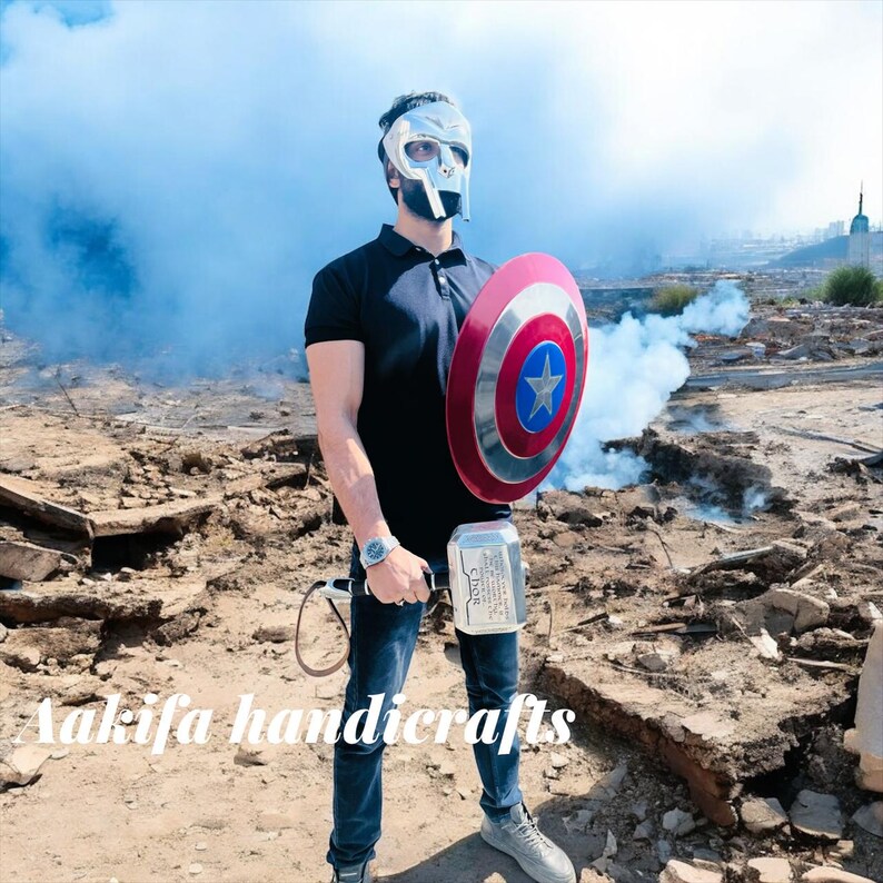 May include: A person wearing a silver mask, black shirt, and blue jeans holds a red, white, and blue shield with a star and a silver hammer. The image has the text "Aakifa handicrafts".