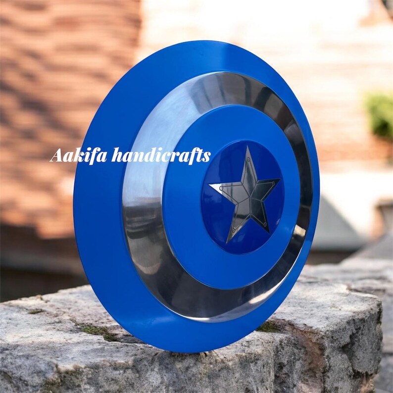 May include: A blue and silver shield featuring a central star design. The shield has a series of concentric circles in blue and silver. The text "Aakifa handicrafts" is visible on the shield.