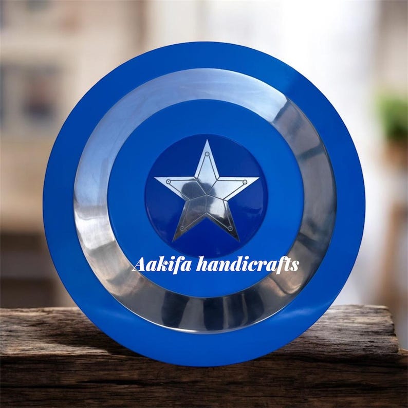 May include: A blue and silver shield featuring a silver star at its centre. The shield has a series of concentric circles in blue and silver. The text "Aakifa handicrafts" is printed on the shield.