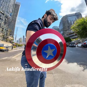 May include: A circular shield in red, white, and blue, featuring a silver star at its centre. The shield has a silver border and is a replica of Captain America's shield.