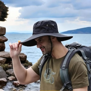 Puede incluir: Sombrero negro para exteriores con ala ancha y correa para la barbilla. El sombrero tiene una copa redonda y está hecho de un material ligero, ideal para la protección solar. Diseñado para actividades al aire libre.