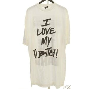 May include: Off-white, short-sleeved t-shirt with the text "I LOVE MY !!B*TCH!!" in black, handwritten-style lettering. The shirt is hanging on a black hanger.