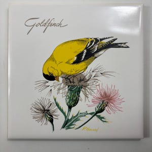 Puede incluir: Azulejo cuadrado con un jilguero amarillo y negro posado sobre una flor de cardo con detalles en rosa y verde. La palabra "Goldfinch" está escrita en cursiva.