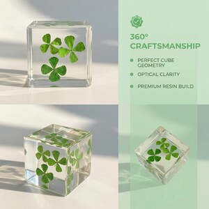 May include: Clear resin cube with four-leaf clovers encased inside. The cube is transparent, allowing the green clovers to be visible from all angles. The image also includes text that reads "360&deg; CRAFTSMANSHIP".