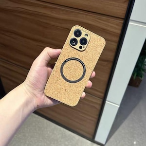 May include: A cork-textured phone case with a gold camera module. The case has a black magnetic ring and the text "KEEP WITH MOBILE MAGNETIC CARD HOLDER". The case is rectangular and has rounded corners.