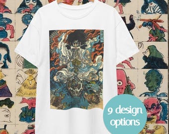 May include: White t-shirt with a colorful graphic print of a Japanese deity. The design features shades of blue, orange, and gold. The shirt is hanging on a wooden hanger against a background of vintage Japanese art. A teal circle with the text "9 design options" is in the lower right.