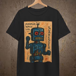 May include: A black short-sleeve t-shirt featuring a graphic print of a blue robot on a tan background. The text "MINIMUM WAGE LOL" appears on the top left and "SURRENDER" on the right side of the robot. The robot has red eyes and a yellow mouth.